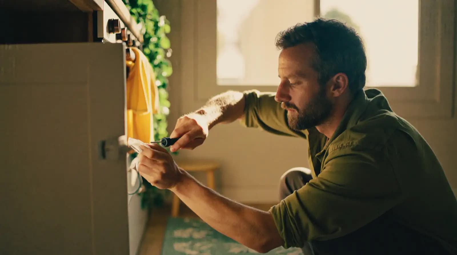 A child-safety latch being fitted to the inside of a kitchen cupboard door.